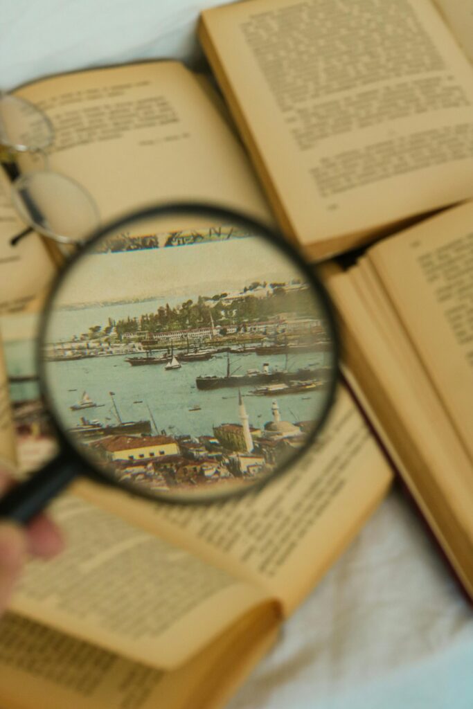 La importancia de la investigación en la vida cotidiana An artistic shot of open vintage books with a magnifying glass highlighting a seascape image.